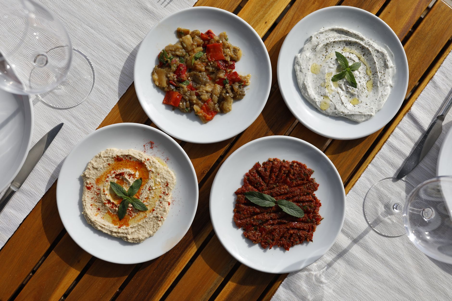 Talíř kyperské meze s grilovaným halloumi, olivami a dipy na dřevěném stole v taverně