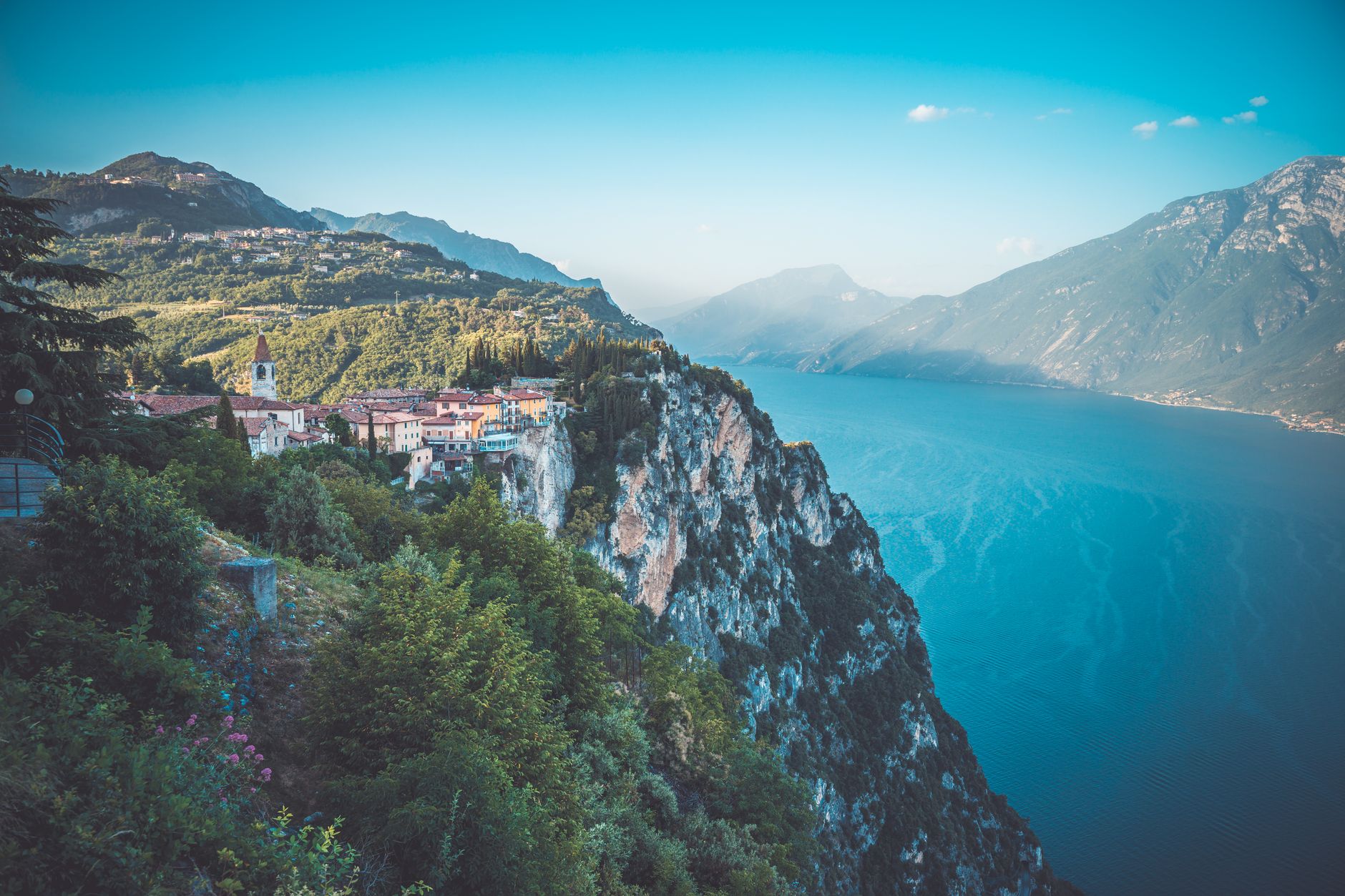 Tyrkysová hladina jezera Lago di Garda s členitým skalnatým pobřežím a alpskými svahy
