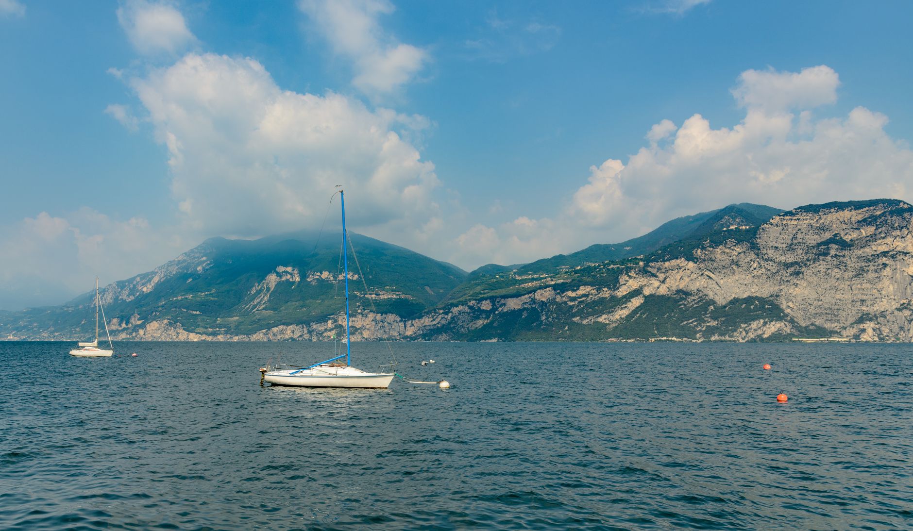 Panoramatický pohled na jezero Lago di Garda s alpskými vrcholy v pozadí a tyrkysovou hladinou