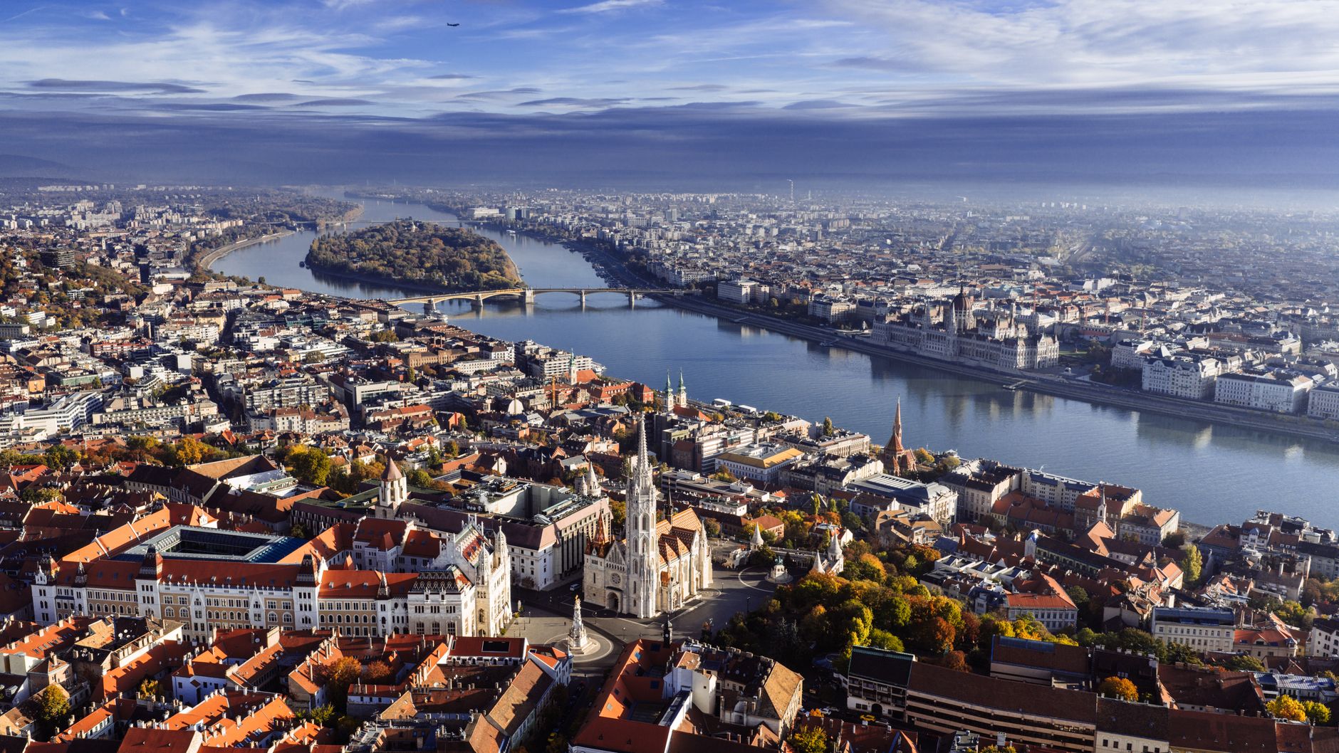Panorama Lince s řekou Dunaj, barevnými domy na nábřeží a kopcem Pöstlingberg v pozadí