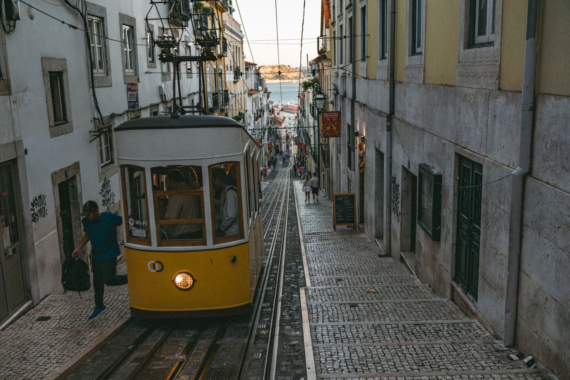 Žlutá historická tramvaj číslo 28 v úzké strmé uličce čtvrti Alfama v Lisabonu