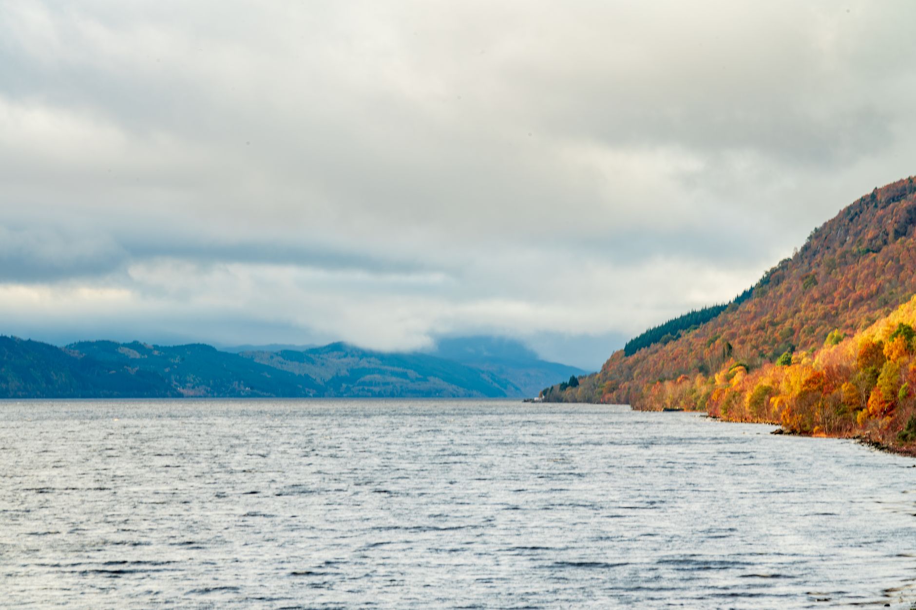 Jezero Loch Ness ve skotské Vysočině s temnou hladinou a zalesněnými svahy v pozadí