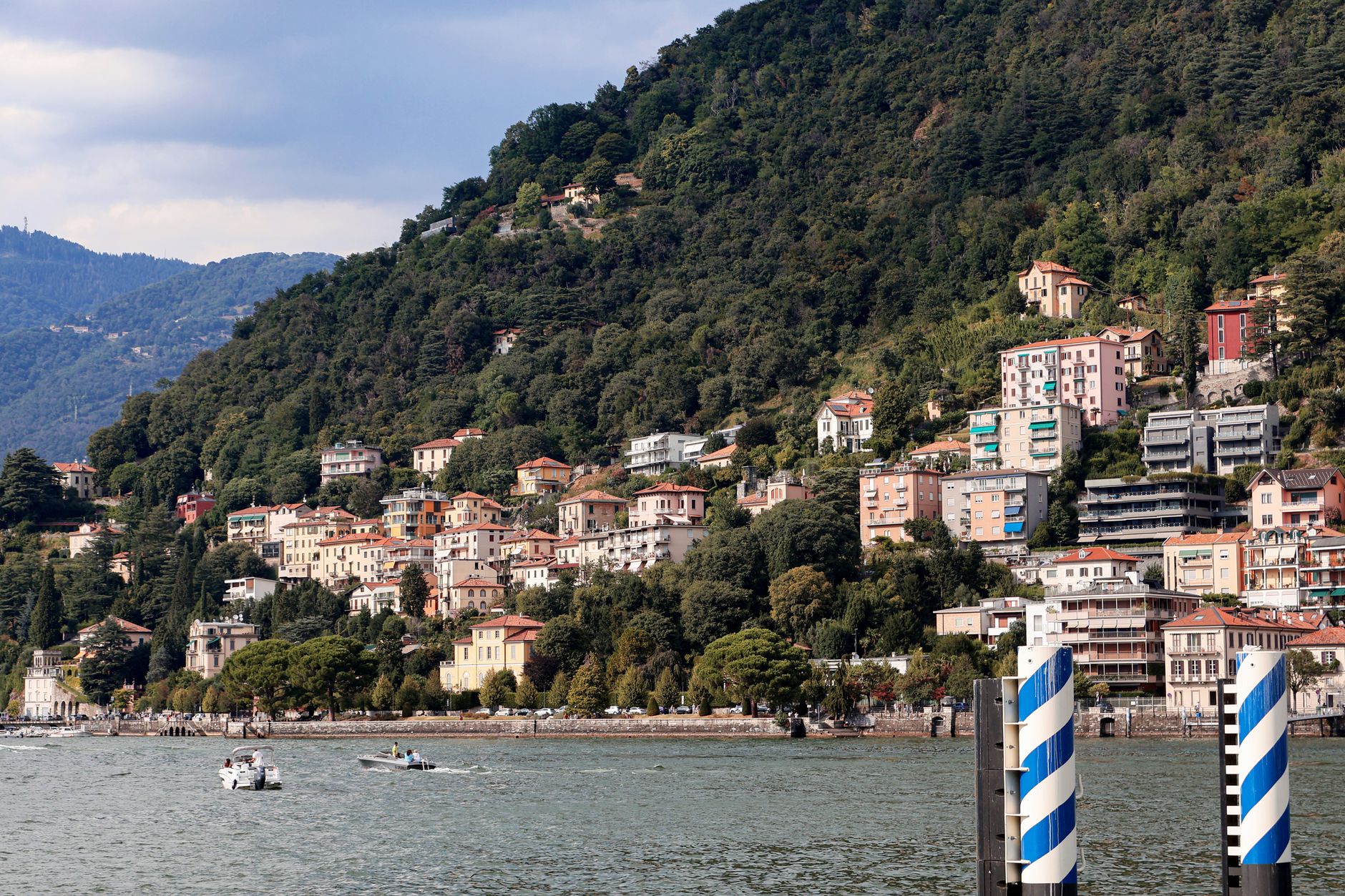 Panorama jezera Como s alpskými svahy spadajícími k vodě a vesničkou na břehu v Lombardii