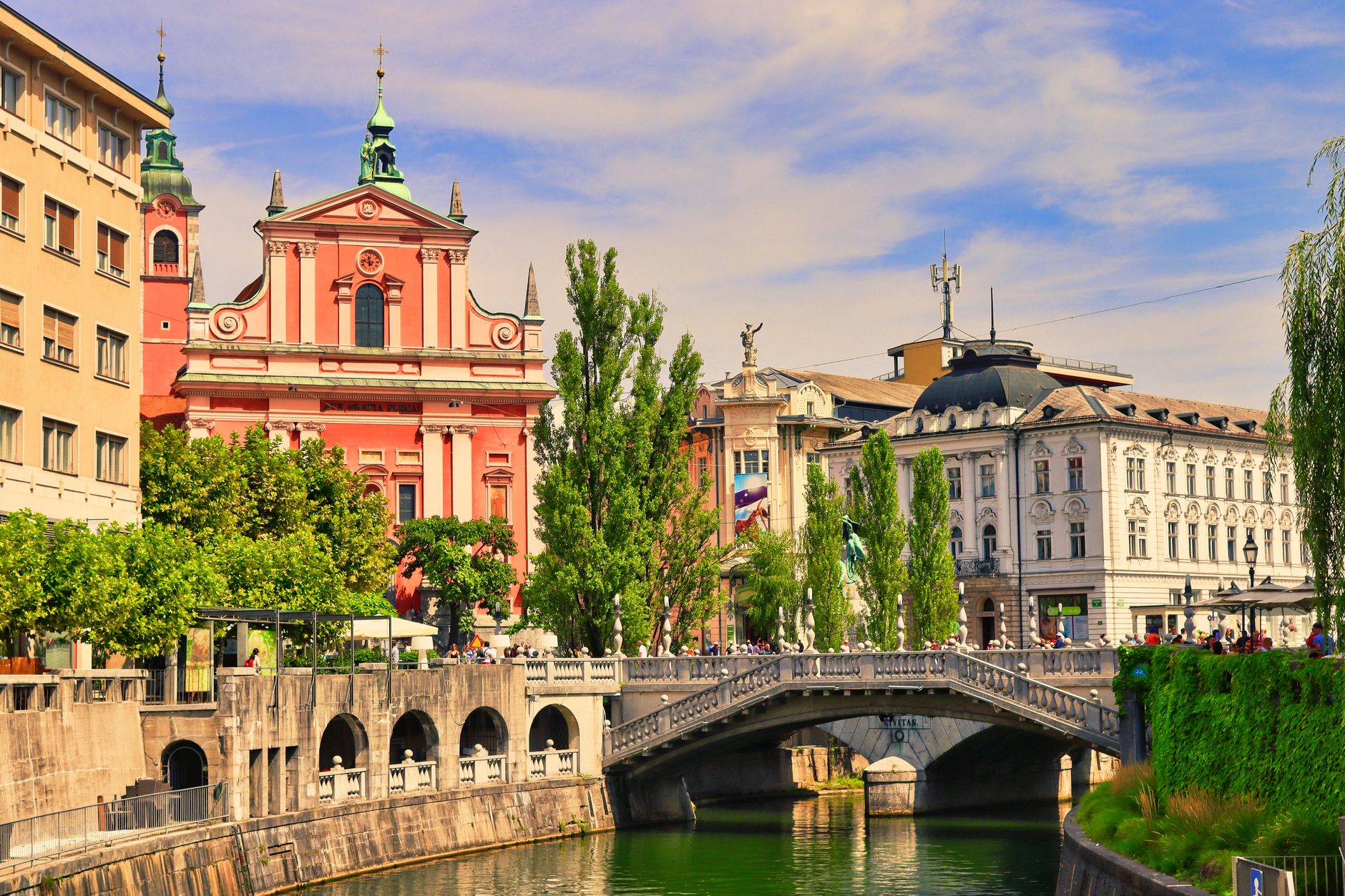 Tromostovje (Trojmostí) přes řeku Ljubljanicu v centru Lublaně s růžovým kostelem v pozadí