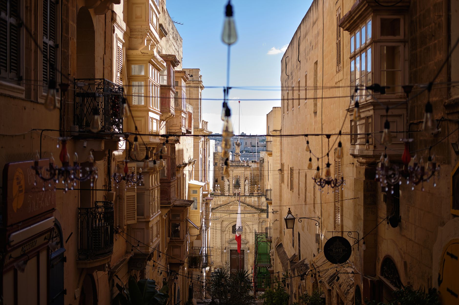Úzká kamenná ulička s tradičními maltskými dřevěnými balkony v barokní zástavbě hlavního města Valletta