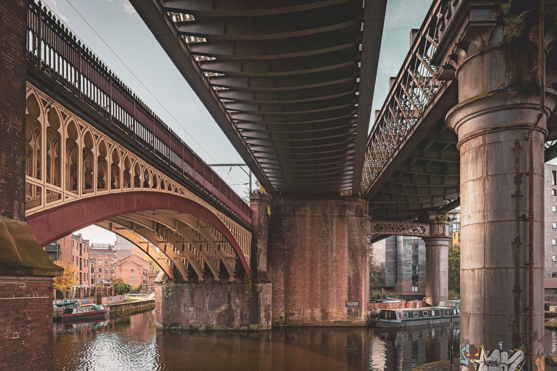 Klidné nábřeží kanálu v industriální čtvrti Castlefield v Manchesteru s mosty