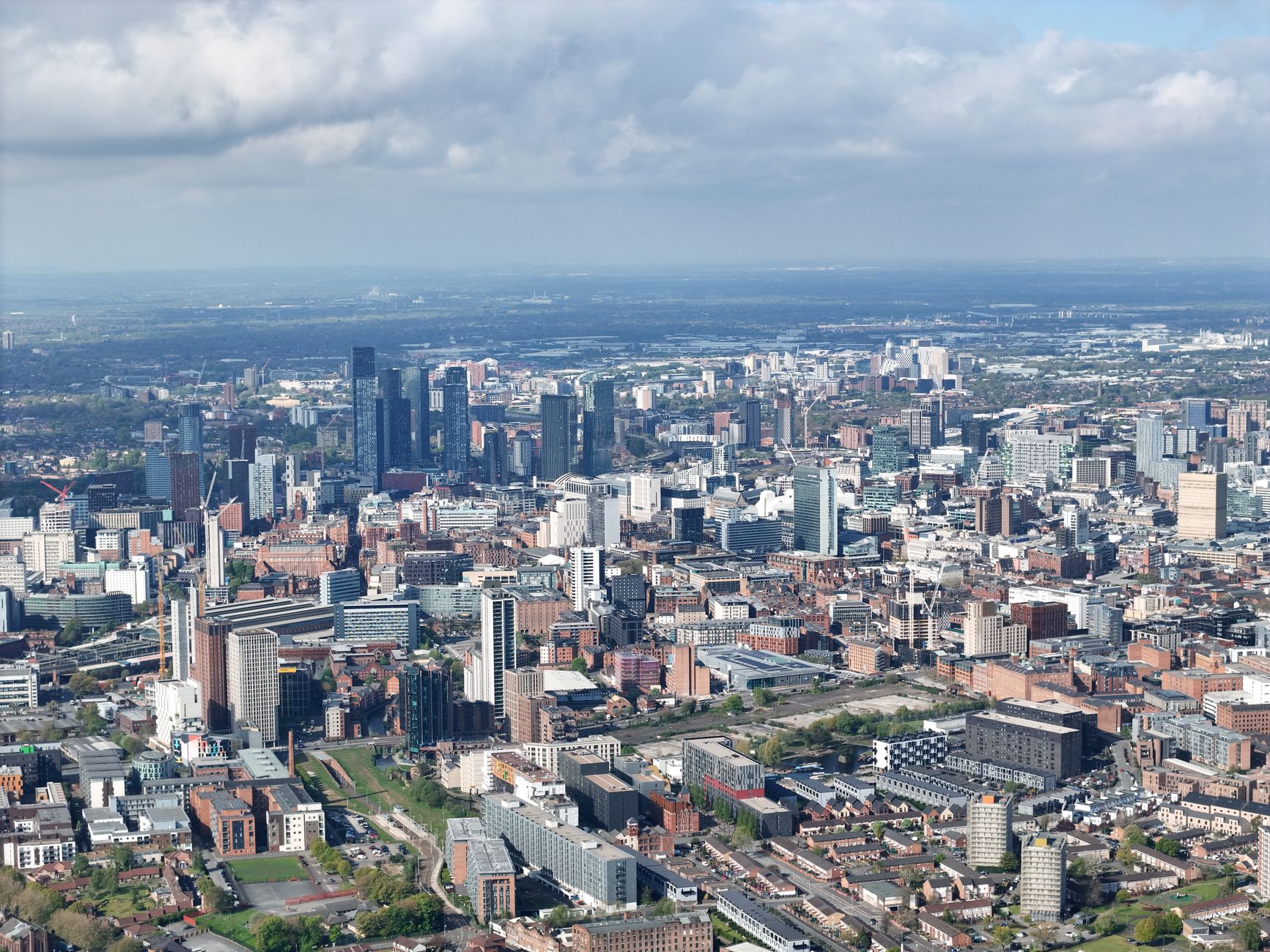 Panorama Manchesteru s historickou radnicí a moderními mrakodrapy za soumraku
