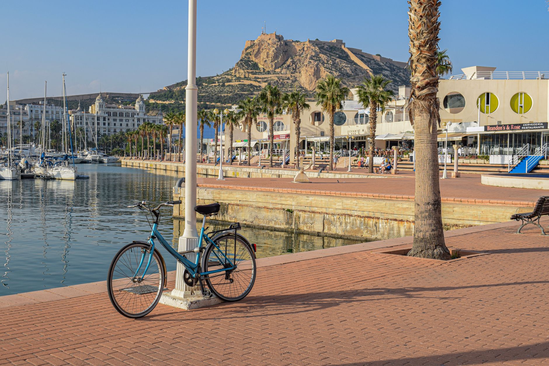 Klidná promenáda u laguny Mar Menor s palmami a kotvícími loďkami za soumraku