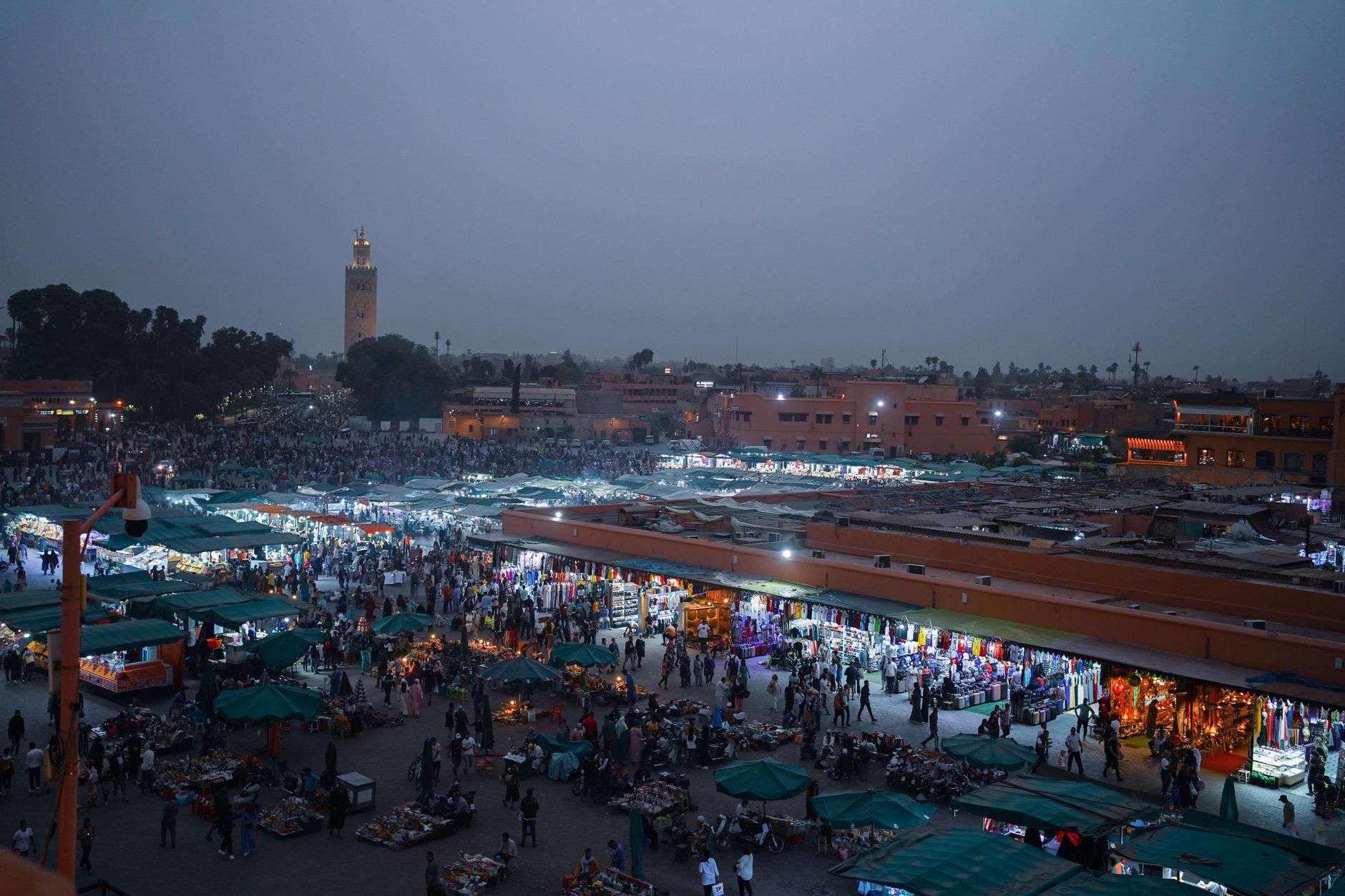 Pohled na náměstí Jemaa el-Fna v Marrákeši za soumraku s minaretem Koutoubia v pozadí