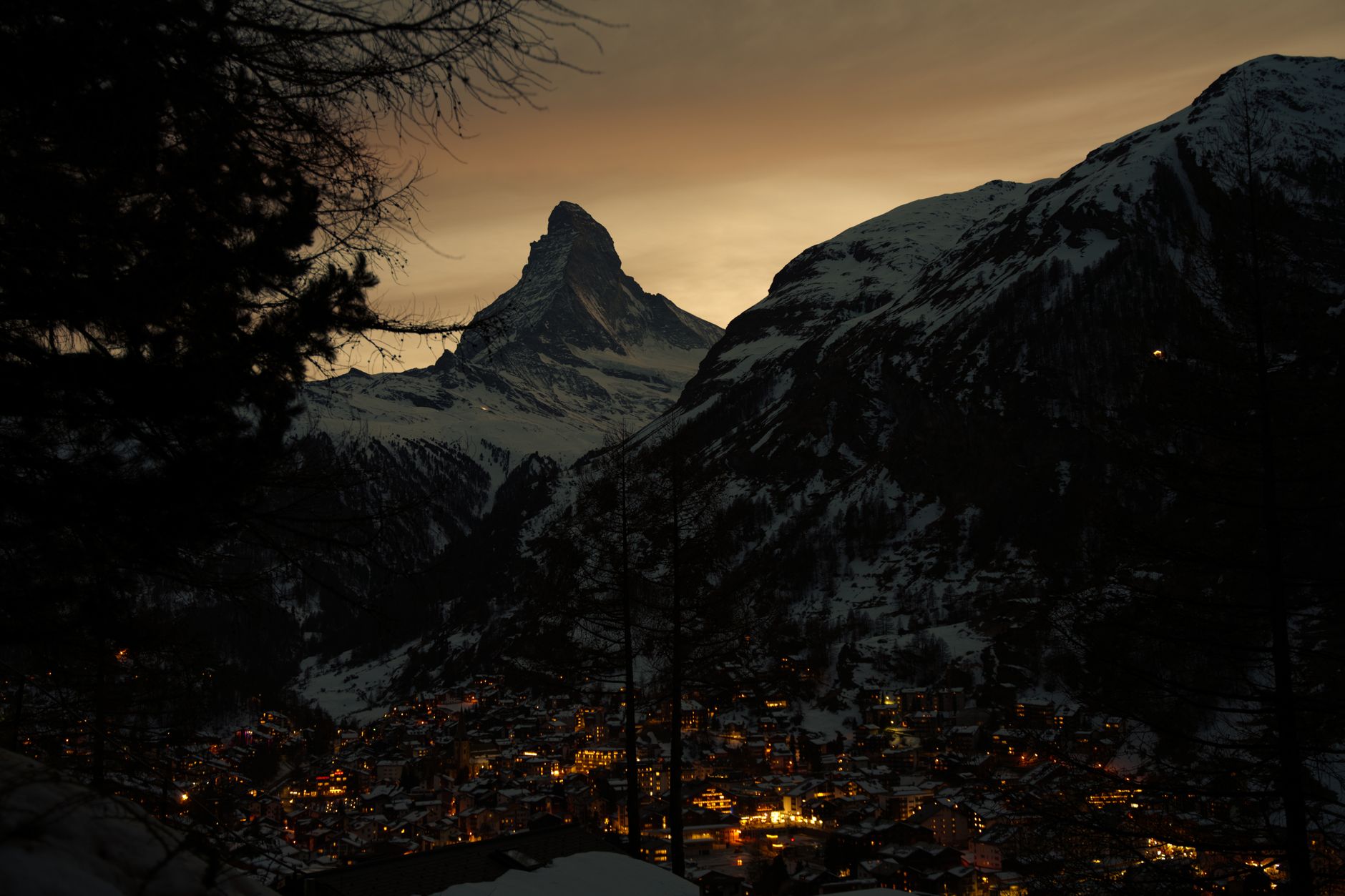 Vesnice Zermatt s dřevěnými chalupami a hlavní ulicí pod horou Matterhorn za soumraku