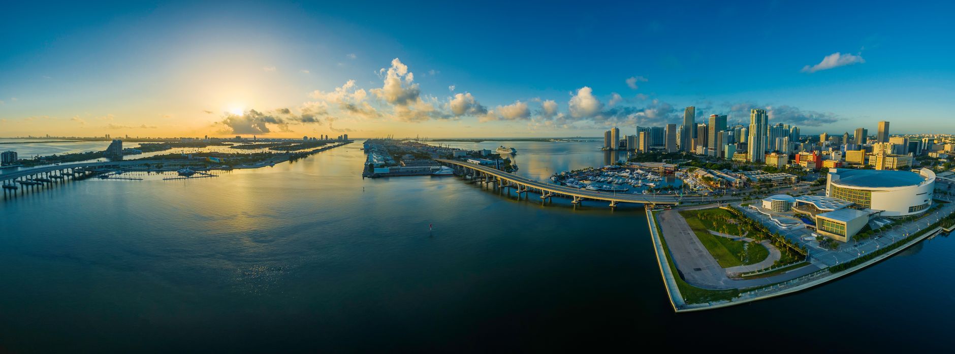 Panorama mrakodrapů Miami se zálivem Biscayne Bay a palmami v popředí za soumraku