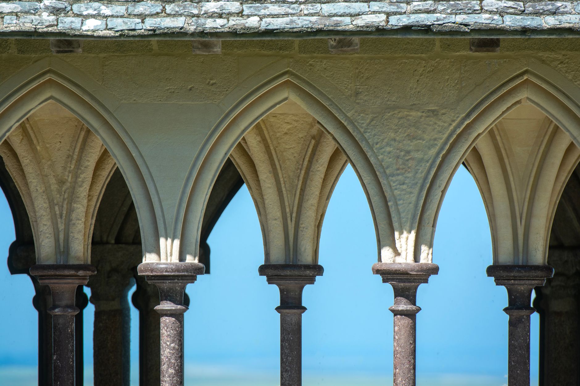 Mont-Saint-Michel za odlivu obklopený rozsáhlými písčinami zálivu pod zataženou oblohou