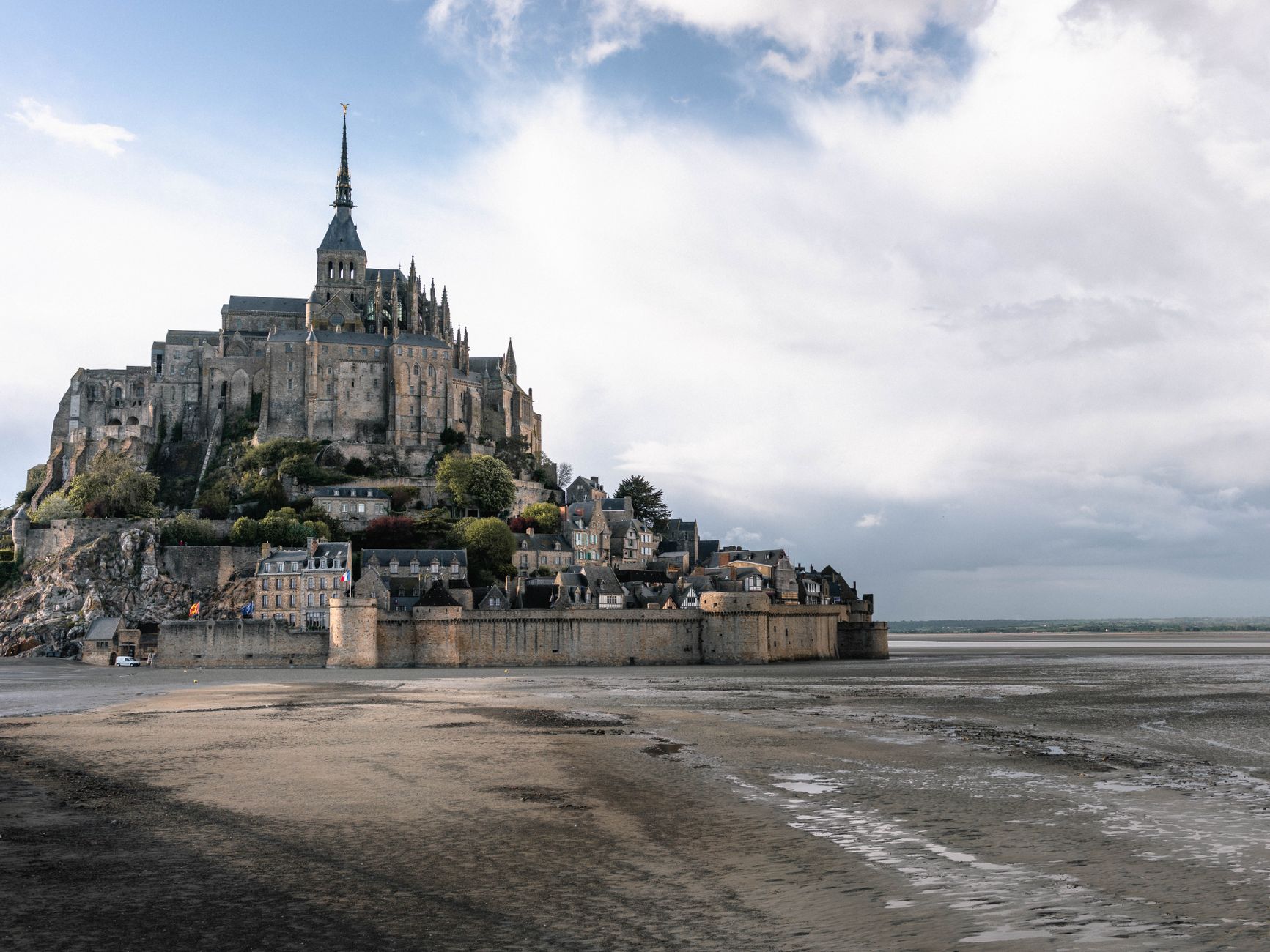 Opatství Mont-Saint-Michel na skalnatém ostrově nad zálivem za přílivu při západu slunce