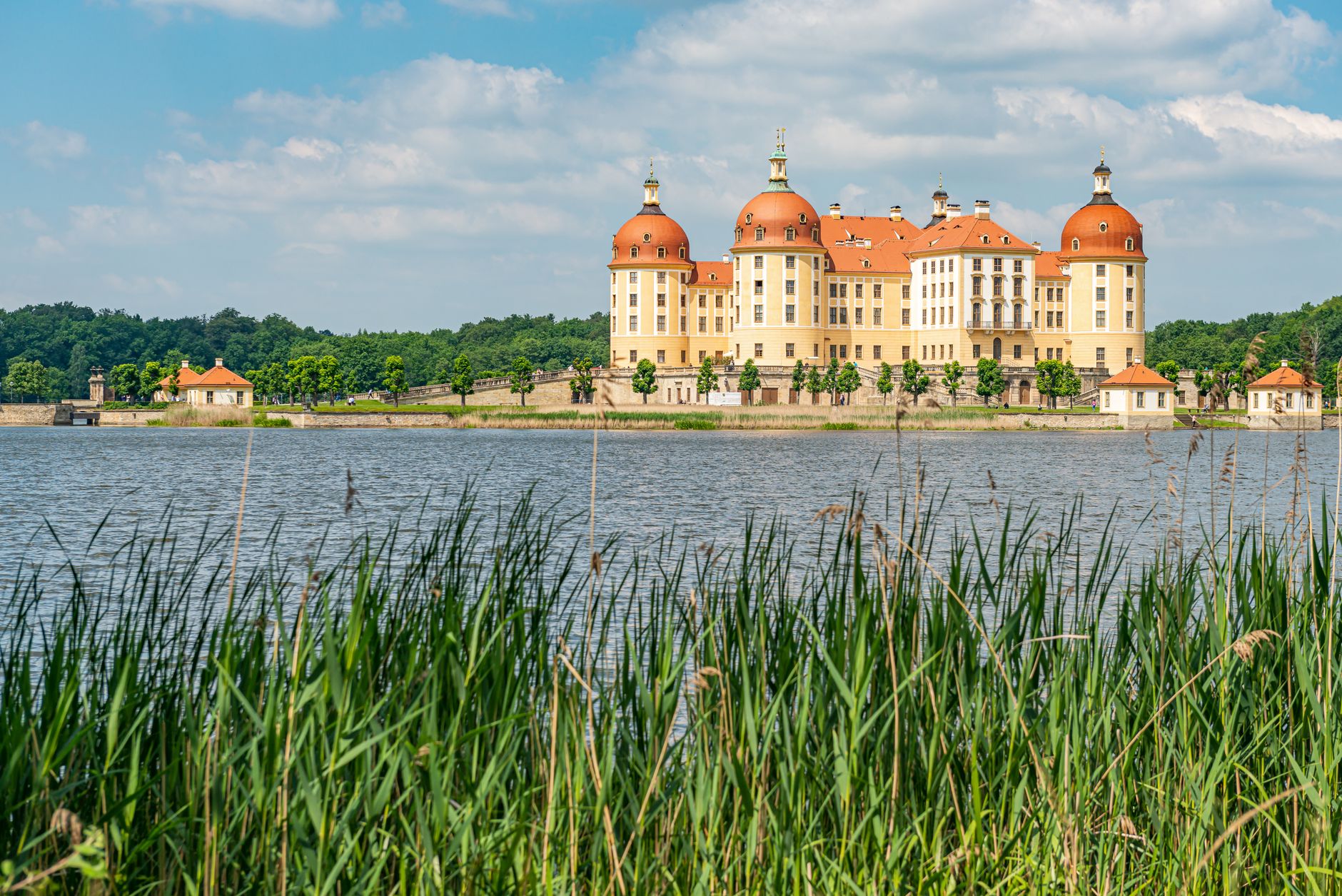 Barokní lovecký zámek Moritzburg uprostřed rybníka se čtyřmi věžemi a kamennou hrází