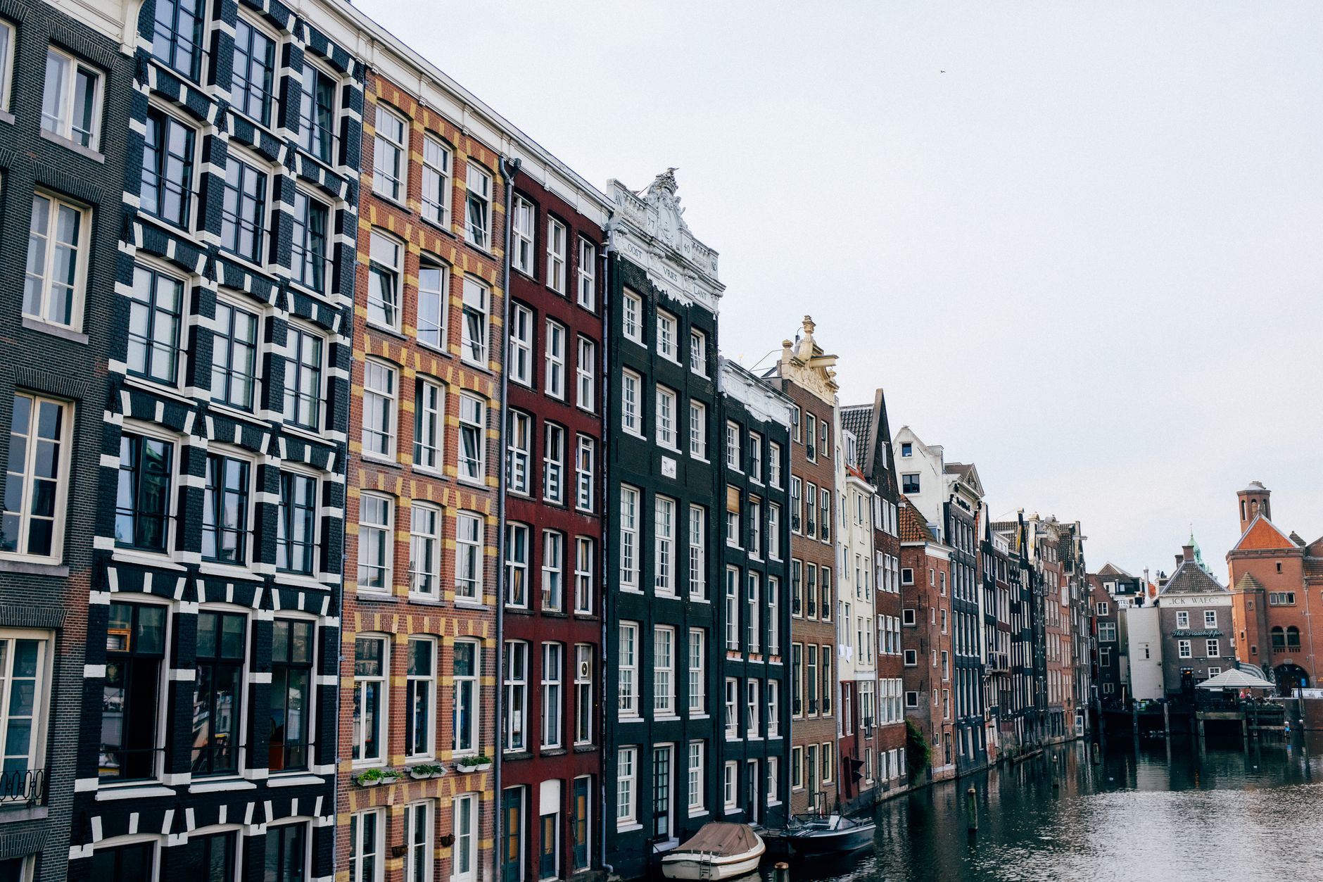 Úzké patrové domy podél kanálu v Amsterodamu se zaparkovanými koly
