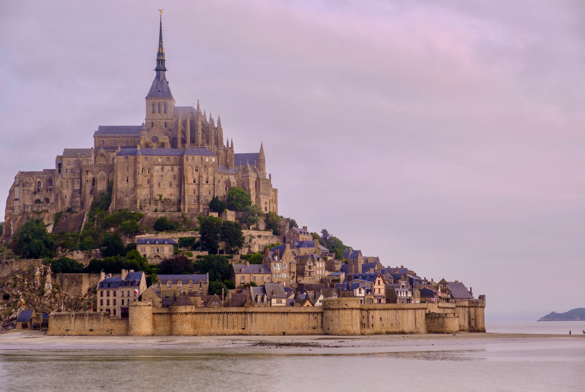 Opatství Mont-Saint-Michel na skalním ostrově obklopené přílivem v Normandii za soumraku