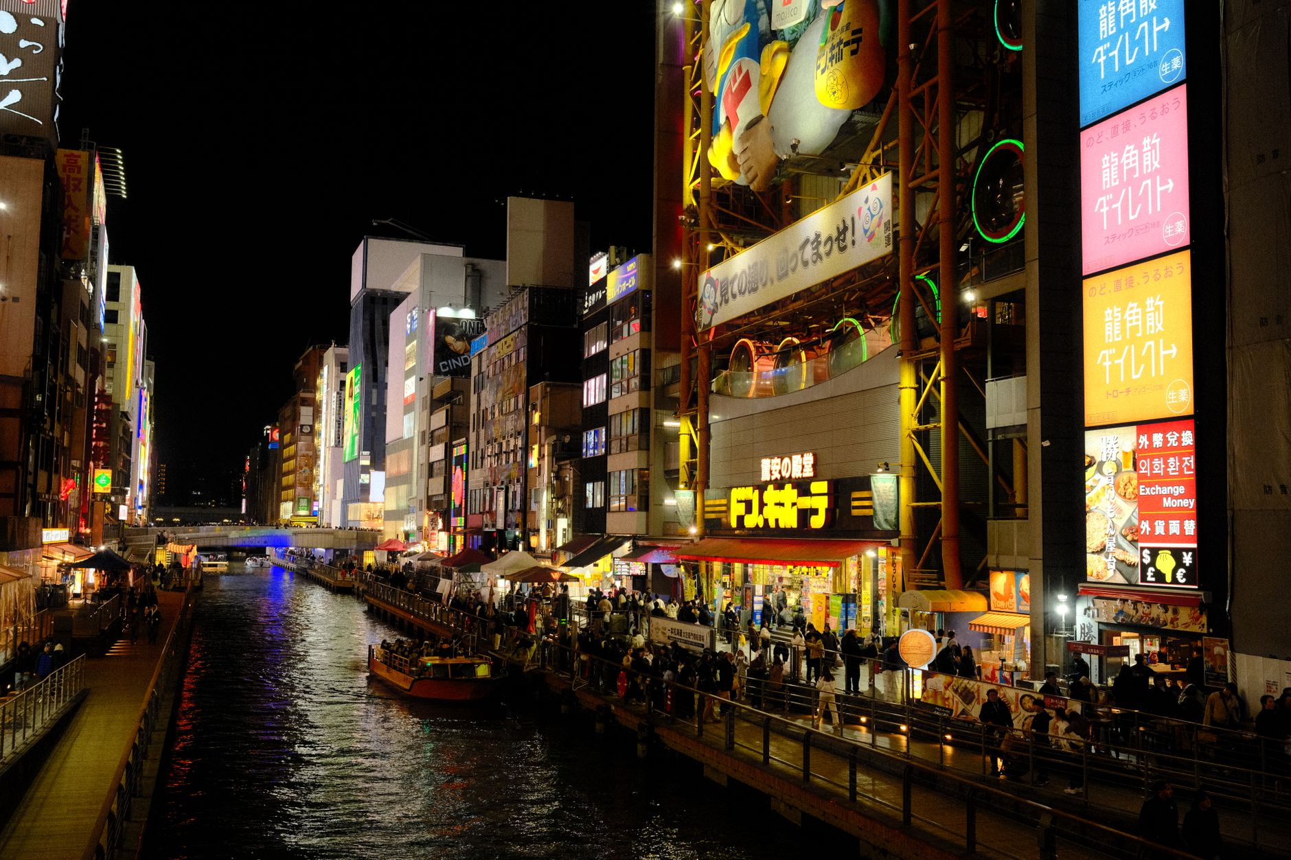 Noční panorama čtvrti Dotonbori v Osace s neonovými reklamami nad kanálem