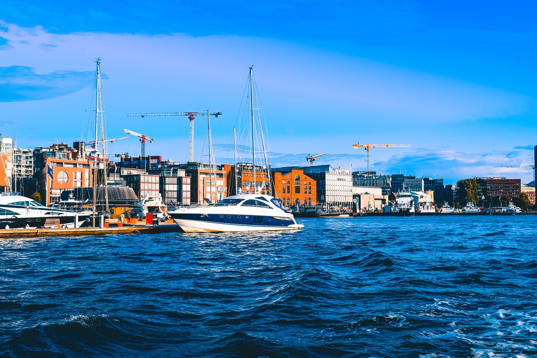 Nábřeží Aker Brygge v Oslu s moderními budovami a zakotvenými loděmi