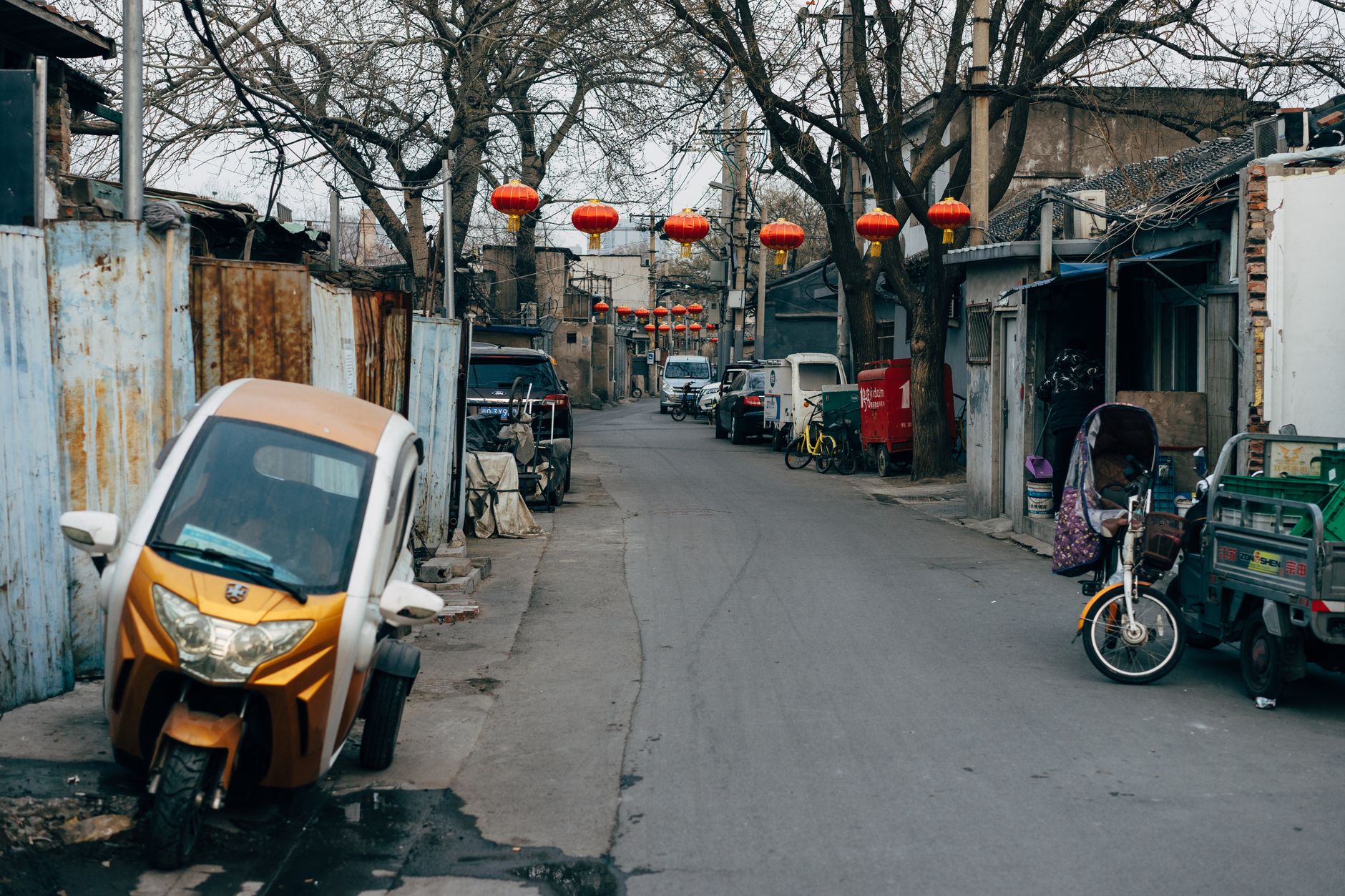 Úzká ulička hutong ve staré části Pekingu se šedými zdmi a tradičními dvorky