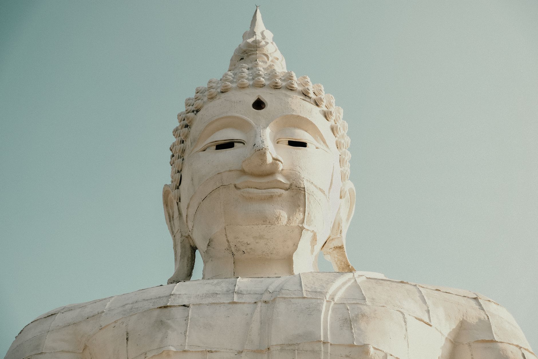 Bílá socha Velkého Buddhy na kopci nad ostrovem Phuket pod modrou oblohou