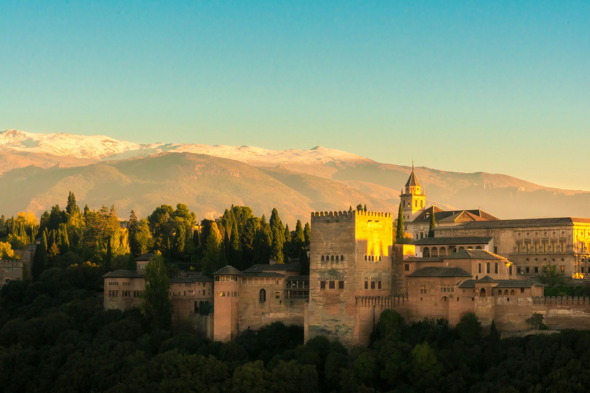 Maurský palác Alhambra v Granadě na pozadí zasněžených hor Sierra Nevada za soumraku