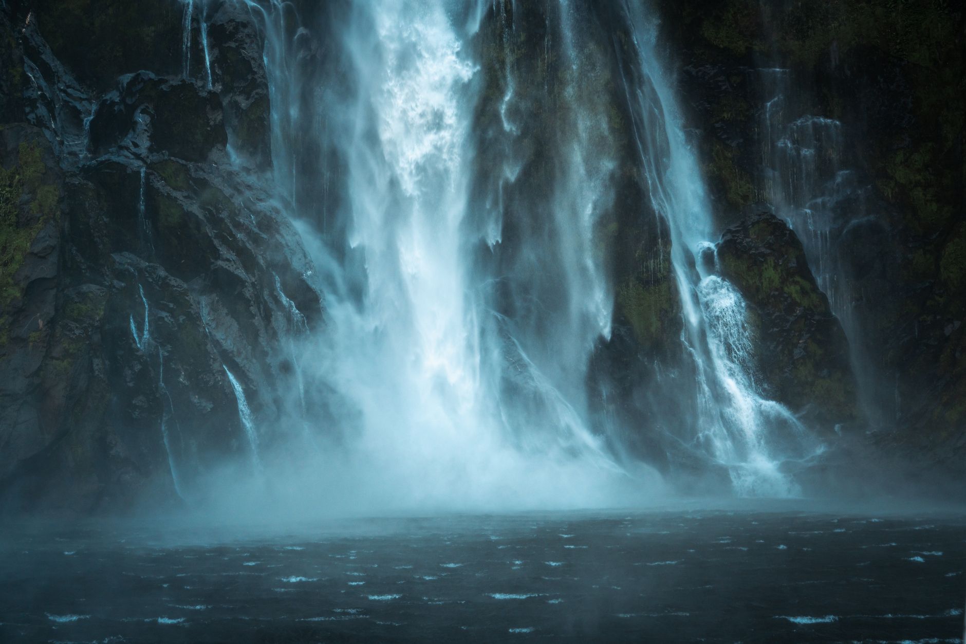 Fjord Milford Sound s vodopádem a strmými skalními stěnami spadajícími do moře