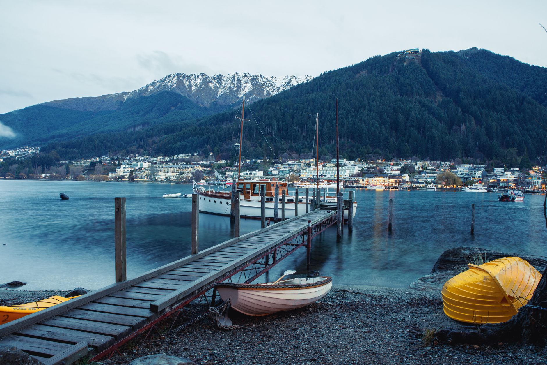 Centrum Queenstownu s nábřežím jezera Wakatipu a horami v pozadí za soumraku