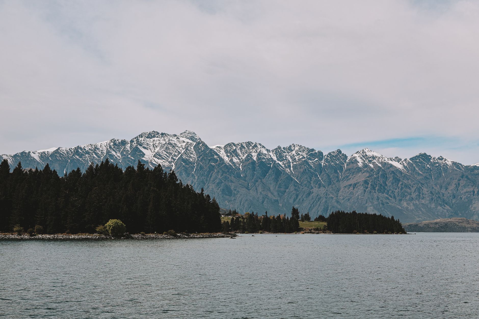 Panorama Queenstownu u jezera Wakatipu s horským masivem The Remarkables v pozadí