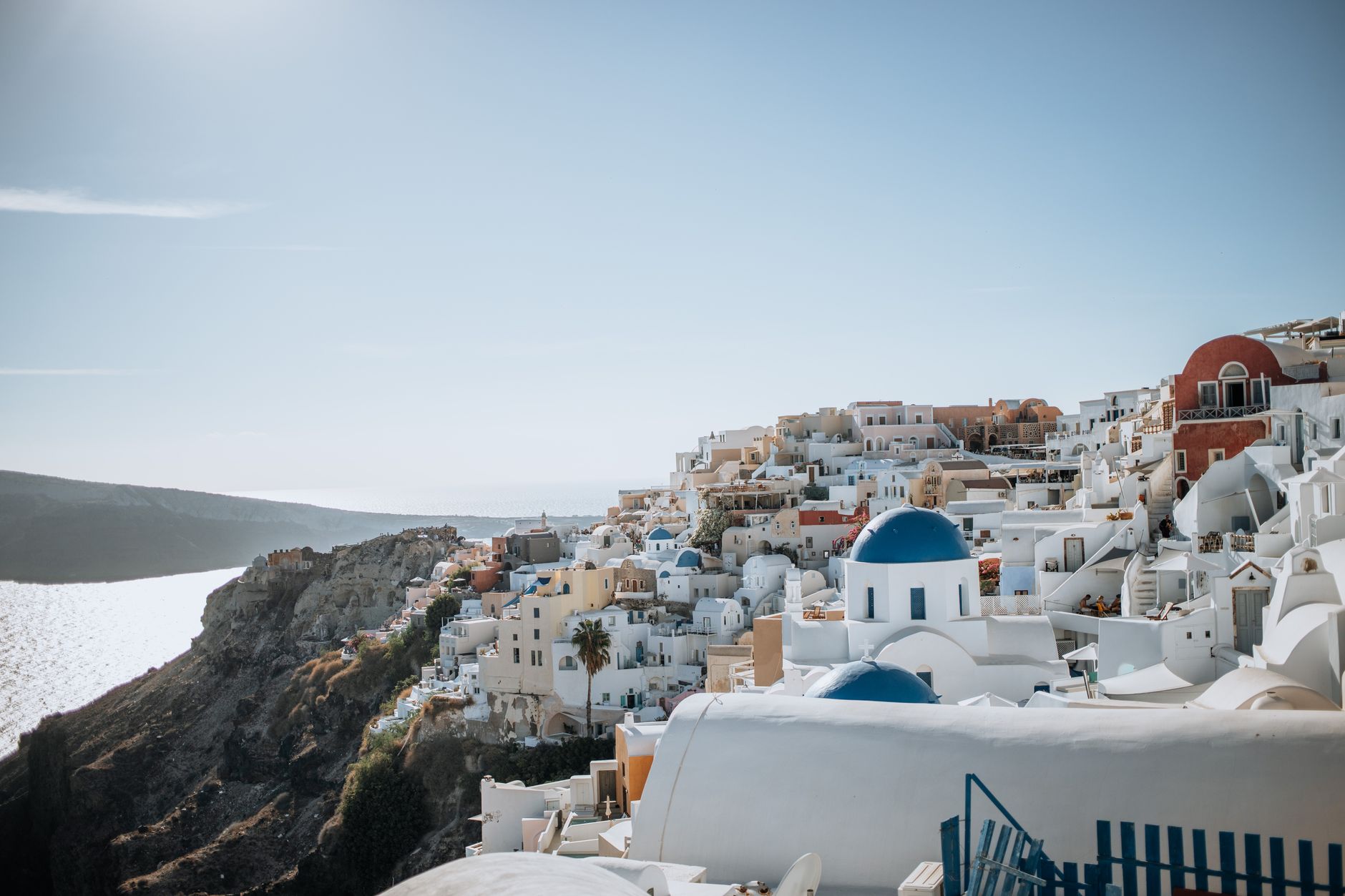 Bílé domky s modrými kupolemi nad mořem na řeckém ostrově Santorini za jasného dne