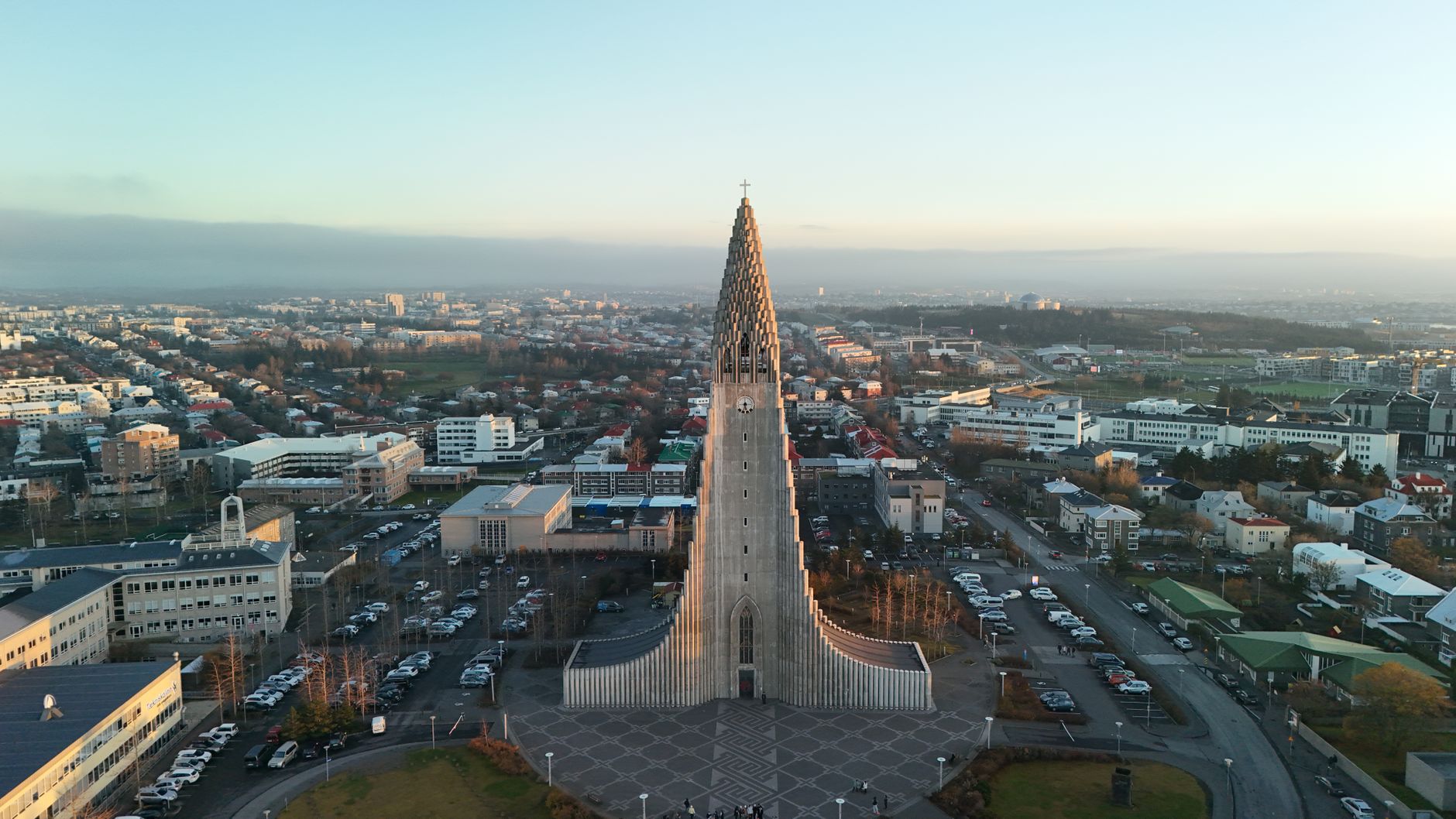 Panorama Reykjavíku s kostelem Hallgrímskirkja a barevnými střechami pod zasněženými horami