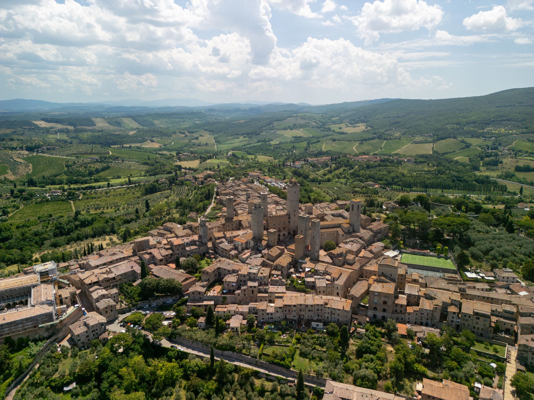 Panorama středověkého města San Gimignano s kamennými věžemi nad toskánskou krajinou