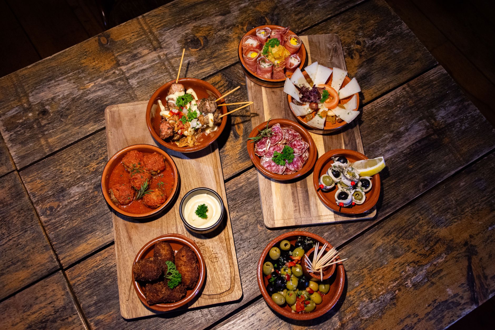 Talíř andaluských tapas s jamón ibérico a olivami na stole