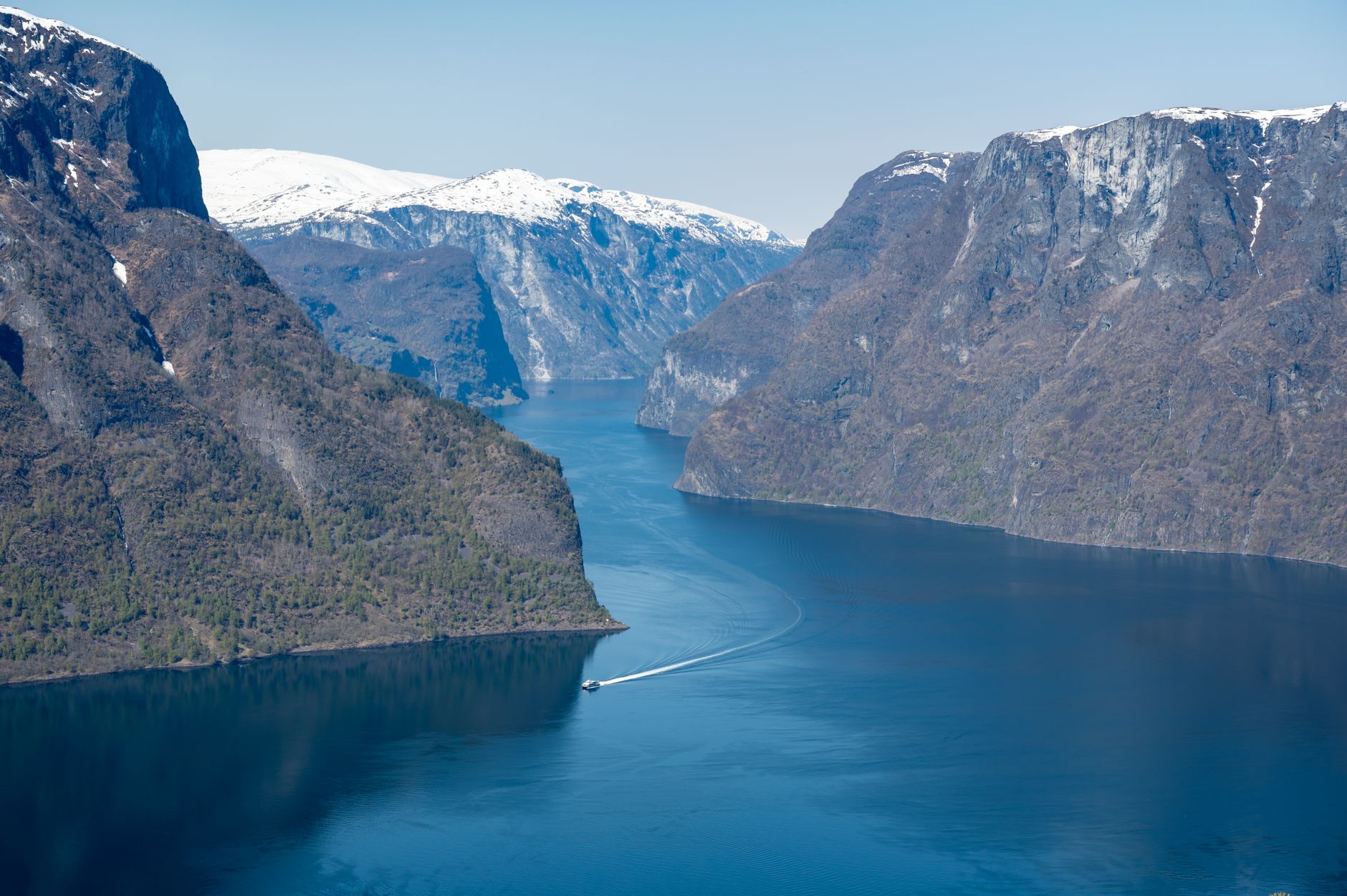 Norský fjord se strmými skalními stěnami a klidnou hladinou v ranním světle