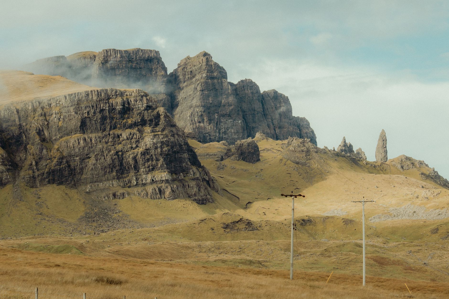Skalní útvar Old Man of Storr na ostrově Skye se zelenými svahy a mraky
