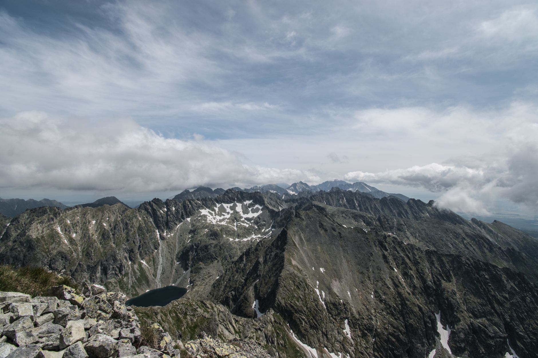 Panorama Vysokých Tater se skalnatými štíty nad horským plesem za jasného dne