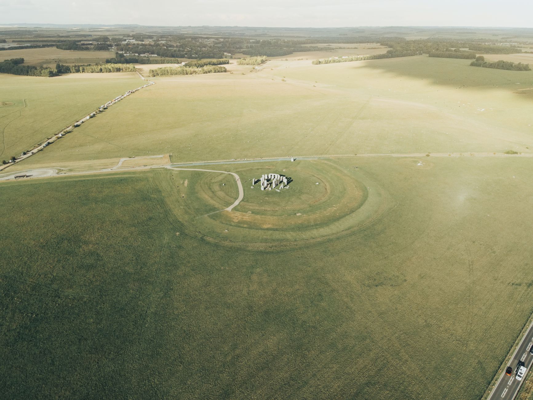 Pravěké mohyly a zvlněná zelená krajina Salisbury Plain kolem Stonehenge