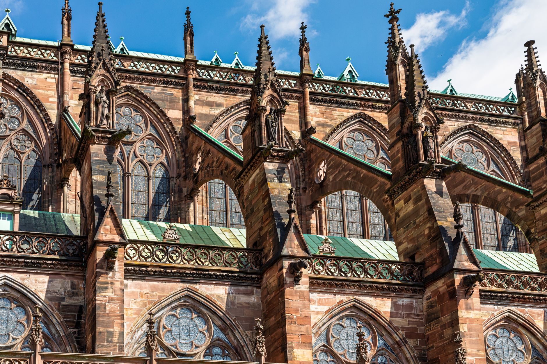 Gotická katedrála Notre-Dame ve Štrasburku z růžového pískovce s jednou věží na pozadí modré oblohy