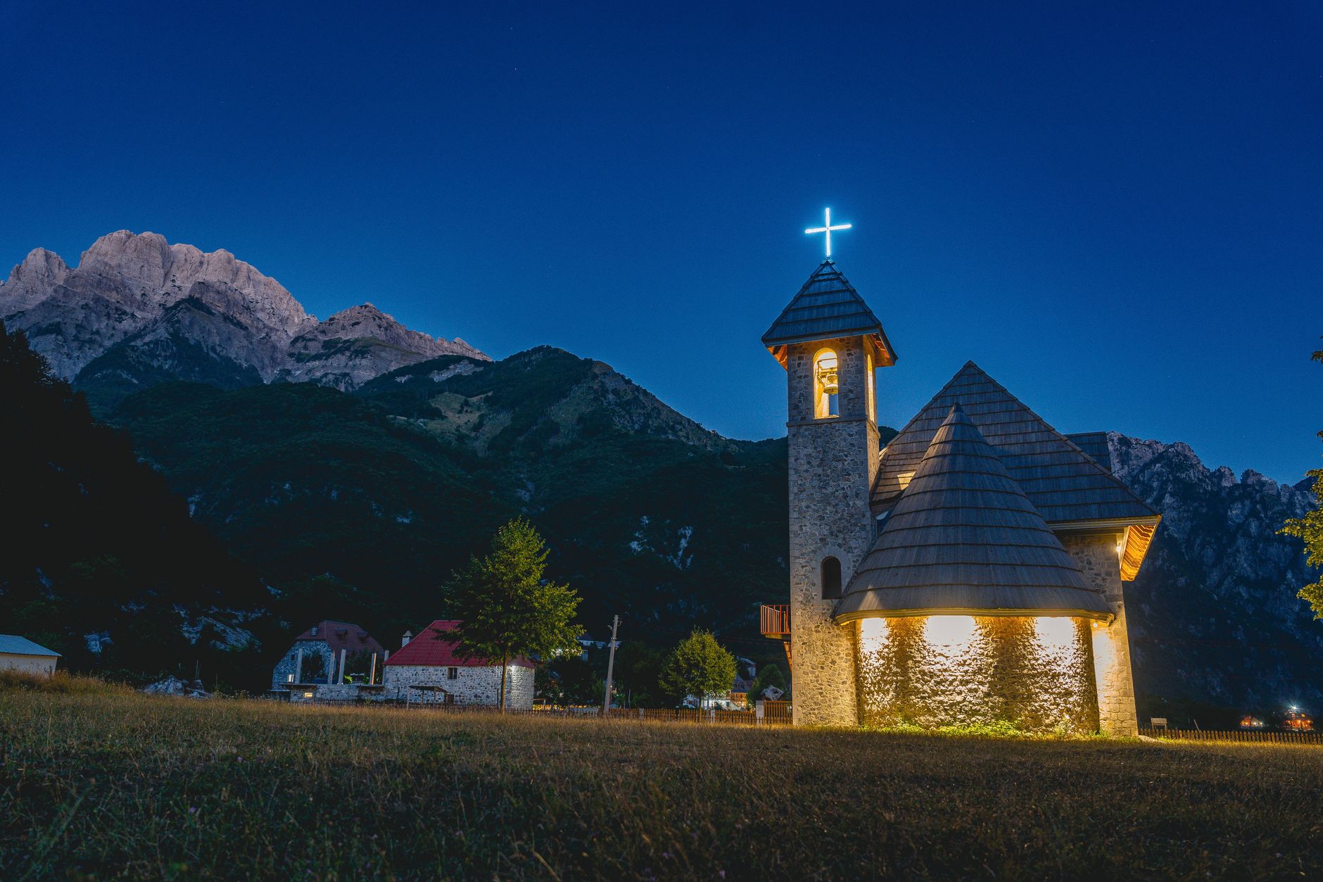Údolí Thethi v albánských Alpách s kamenným kostelem a vrcholky hor Prokletije v pozadí