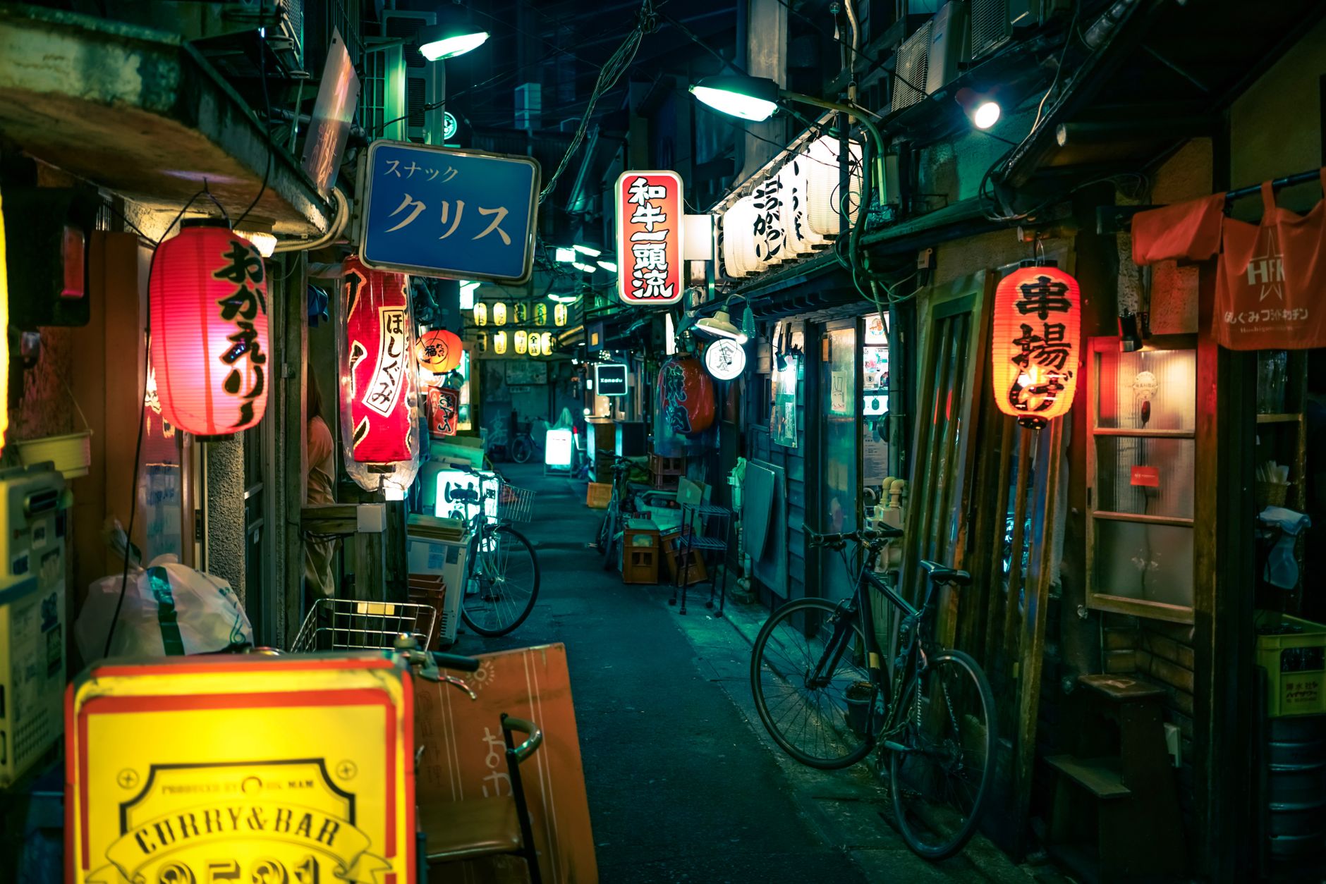 Úzká večerní ulička v Tokiu s lampiony a japonskými cedulemi nad malými podniky
