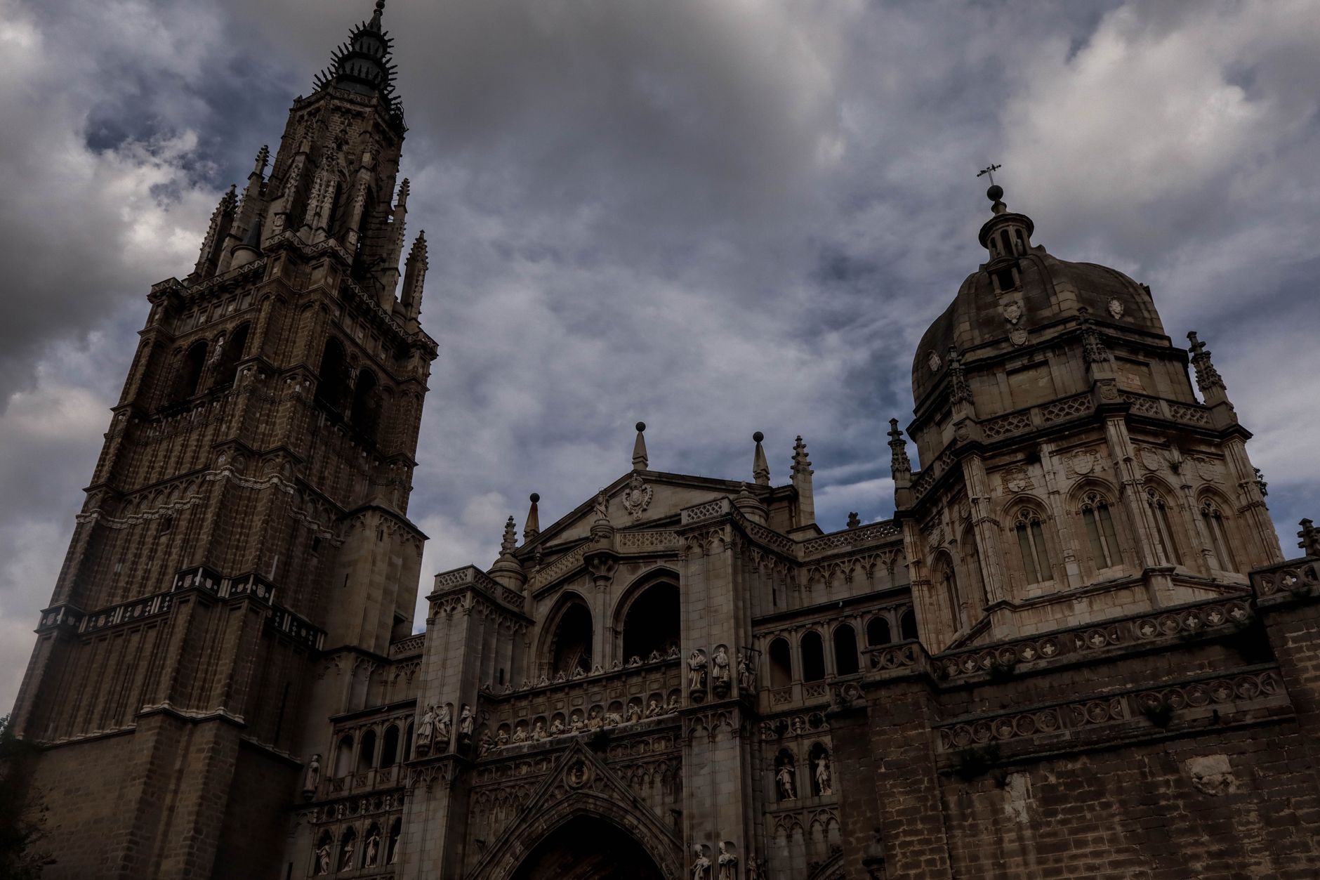Úzká strmá dlážděná ulička ve starém městě Toledo mezi kamennými domy