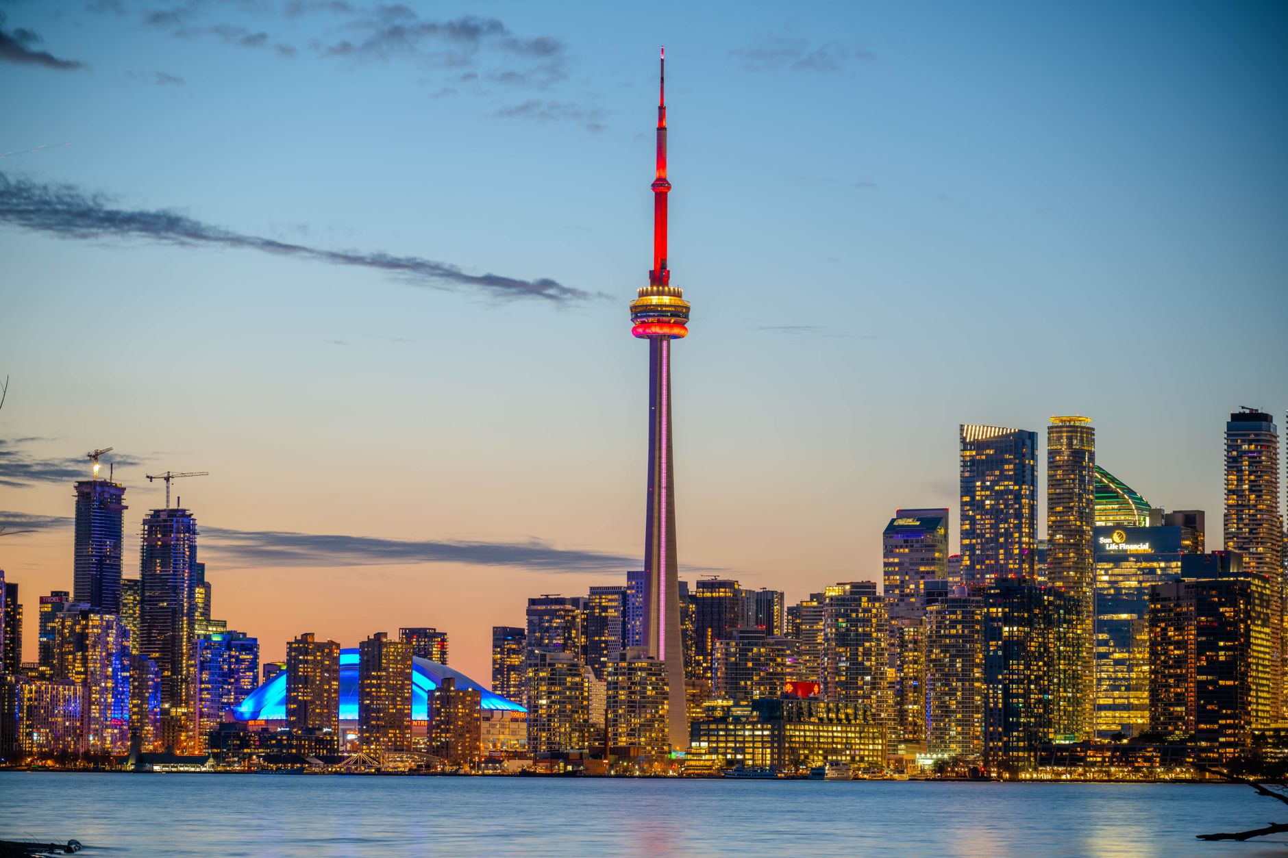 Panorama Toronta s věží CN Tower a mrakodrapy odrážejícími se v jezeře Ontario za soumraku