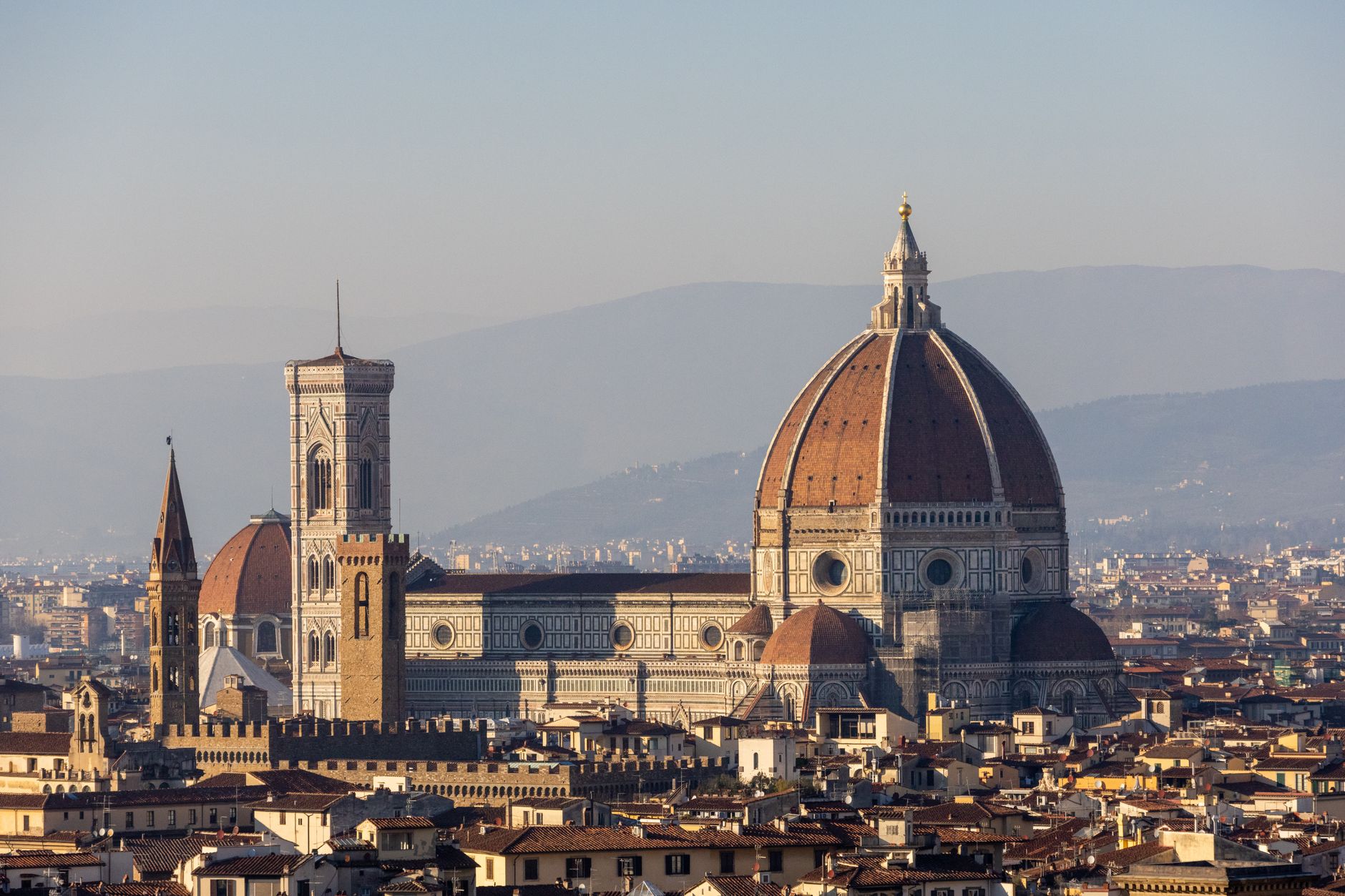 Katedrála Santa Maria del Fiore s červenou kupolí a zvonicí ve Florencii za jasného dne