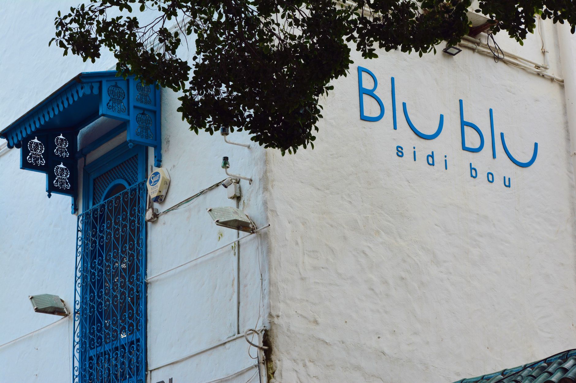 Modré dveře a bílá zeď s kamennou klenbou v Sidi Bou Said v Tunisku