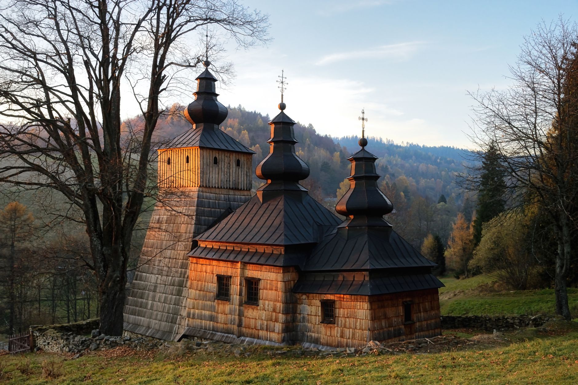 Dřevěný huculský kostelík se šindelovou střechou v zalesněné krajině ukrajinských Karpat