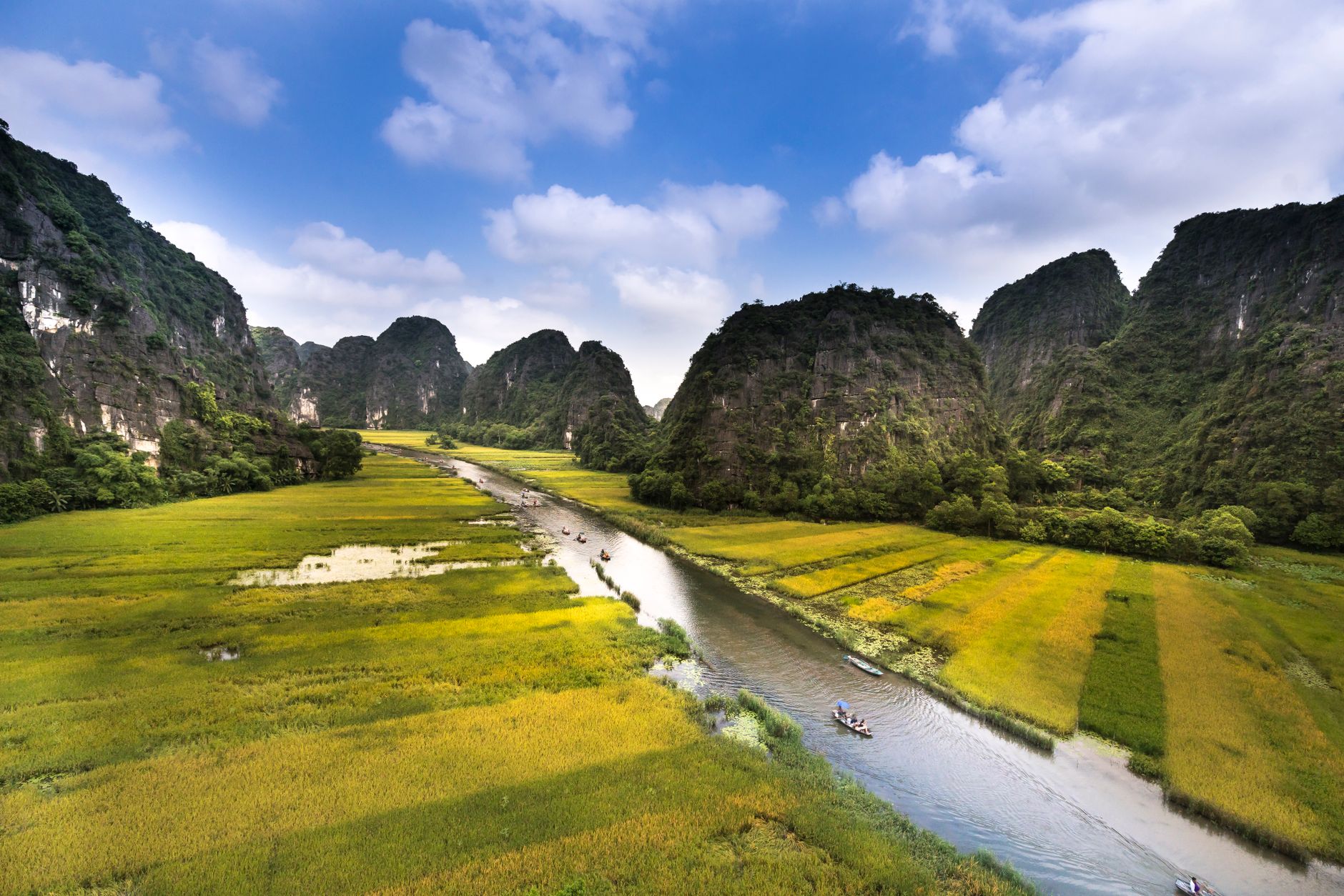 Vápencové věže vystupující z rýžových polí u Ninh Binh ve Vietnamu s loďkou na řece