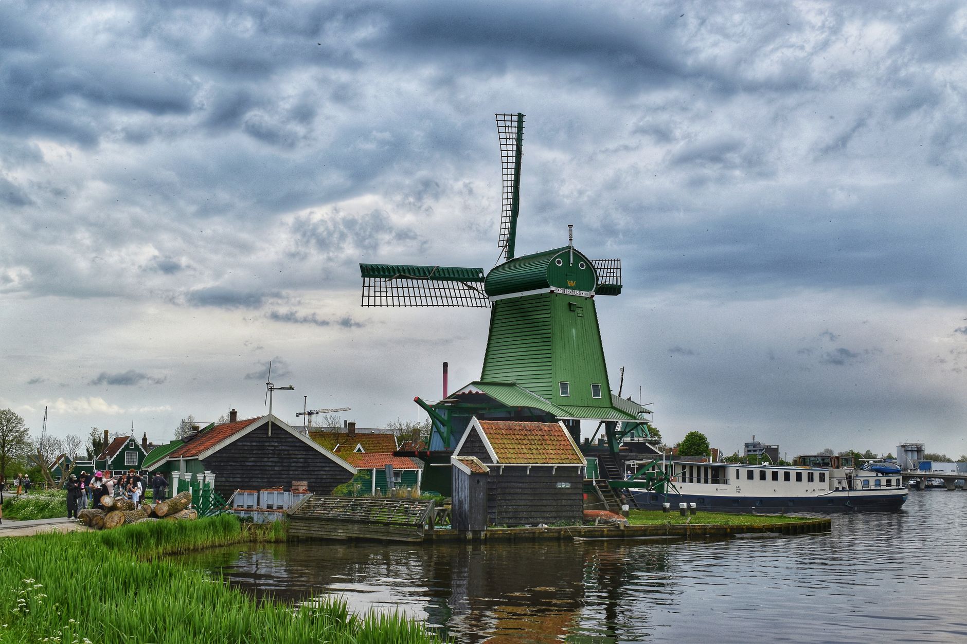 Větrný mlýn s roztaženými dřevěnými lopatkami nad řekou Zaan v Zaanse Schans