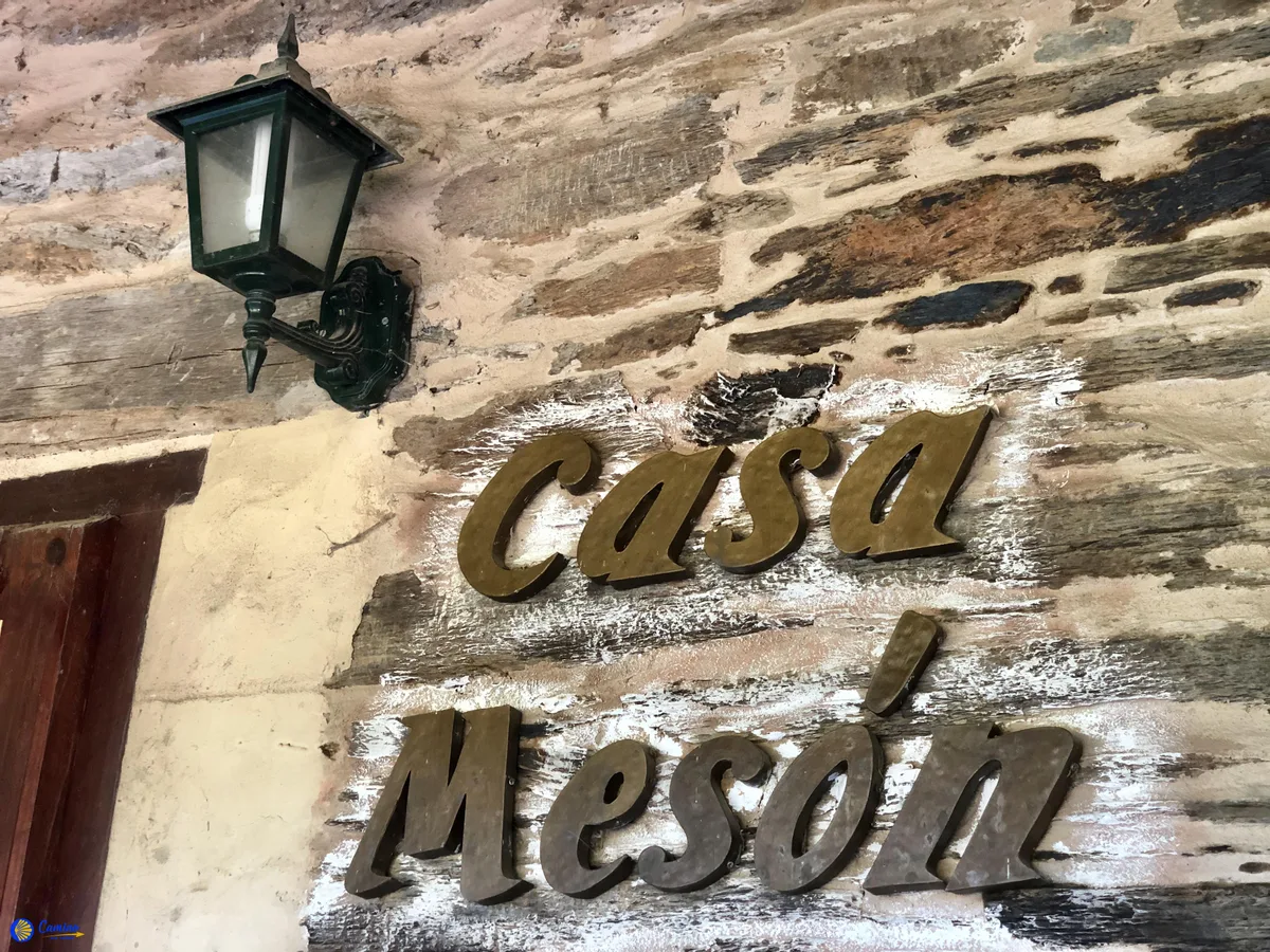 Cesta po Caminu de Santiago se žlutou značkou mušle a poutníkem s batohem